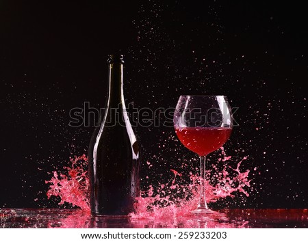 bottle and glass with red wine, red wine splash, wine pouring on table on dark black background, big splash around Glass and bottle of red wine splash on black