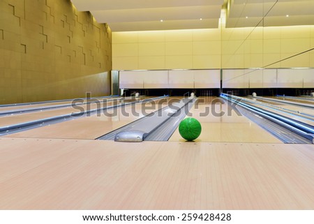 Bowling ball lying on bowling alley\
It will be strike. Green bowling ball rolling along bowling alley