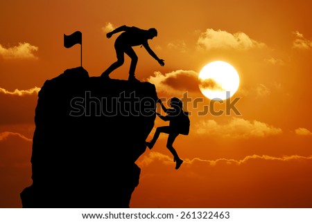 The joint work teamwork of two people man and girl travelers help each other on top of a mountain climbing team, a beautiful sunset landscape.