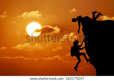 The joint work teamwork of two people man and girl travelers help each other on top of a mountain climbing team, a beautiful sunset landscape.