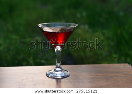 red cocktail in apple garden on the table