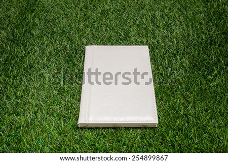 White leather book lying on the green grass
