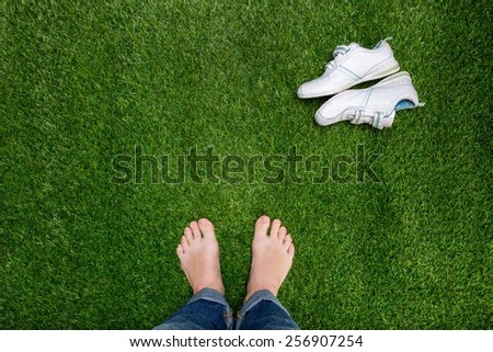 Feet resting on grass with slying sneakers
