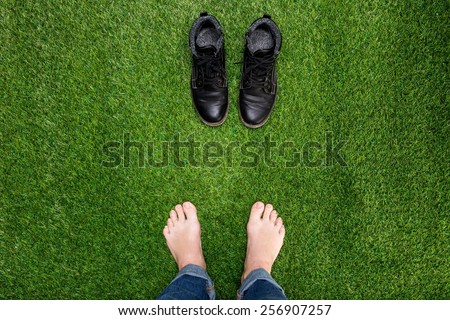 Feet resting on green grass with standing opposite boots