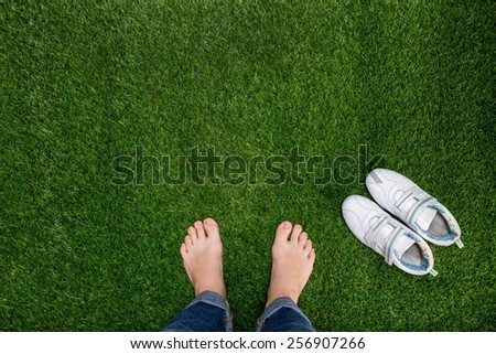 Feet resting on green grass with sneakers
