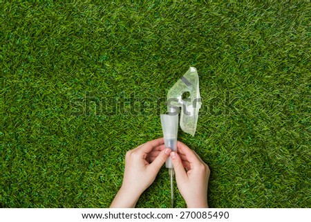 Asthma allergy inhaler sprayer over green grass. Breathing fresh air in nature concept. Horizontal photo.