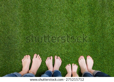 Family legs standing on green grass having fun outdoors in spring park.