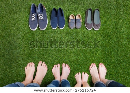 Family legs standing on green grass having fun outdoors in spring park with theirs shoes