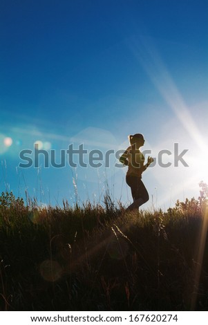 Silhouette of a female jogger with sun flare