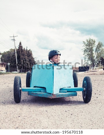 Young boy sitting in a blue homemade soap-box car