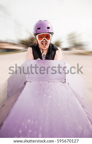 young girl screaming as she\'s rolling down a hill in a homemade soap-box car