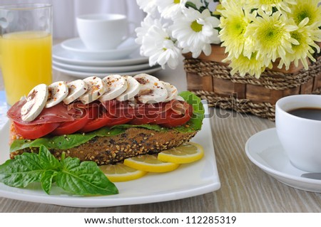 Sandwich with ham and mushrooms with a cup of coffee and juice