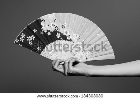 black and white feminine hand and a Japanese fan