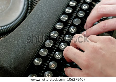 Hands are typing on vintage dirty black typewriter