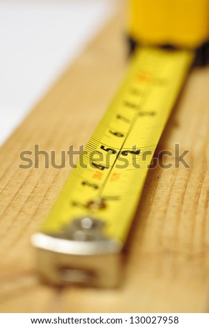A yellow tape measure laid out on a block of wood