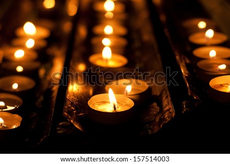 Rows of brightly burning votive candles
