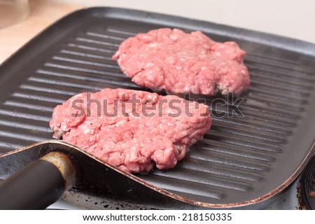Homemade burger patties cooking on a grill-pan