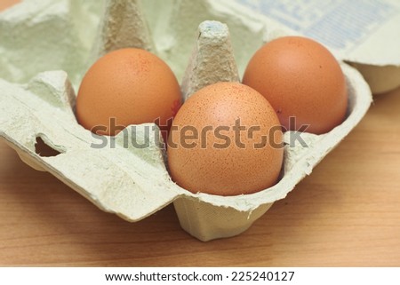 Three free-range chicken eggs in a green egg box
