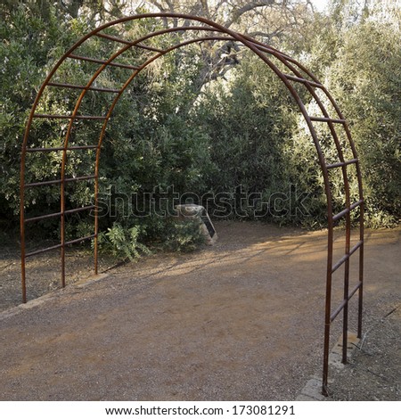 Alley with overhanging metal arch in arboretum