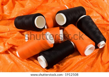 Bobbins of black and orange threads on the orange cloth