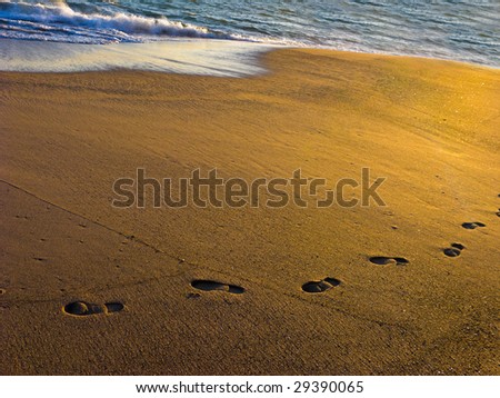 Beach Sand with Wet Footprints on Ocean Shore at Dusk