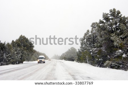 Cars Moving carefully in Winter Blizzard on Icy Road