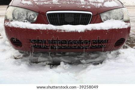 Car front bumper and headlights covered with icy snow
