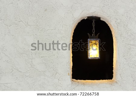 Decorative outdoor  lamp in stucco wall window in the night