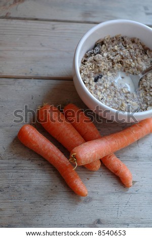 white breakfast bowl with milk, cereal and carrots on a bright wooden table in natural light
