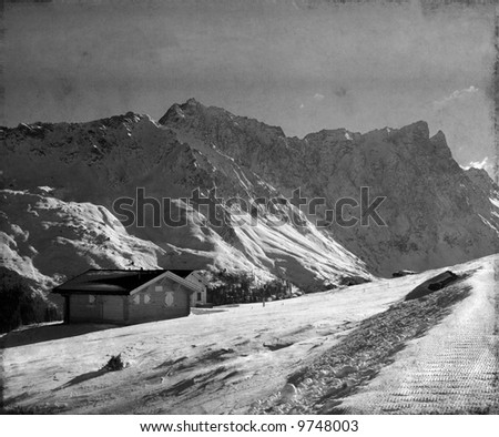 monochrome image of two simple houses on a mountain in the central european alps on a freezing winter\'s day