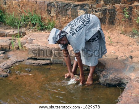 African woman in traditional printed dress washing hands. L
