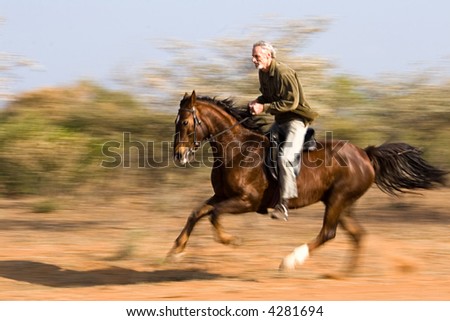 stock photo Senior man riding the horse in the bush panning shot
