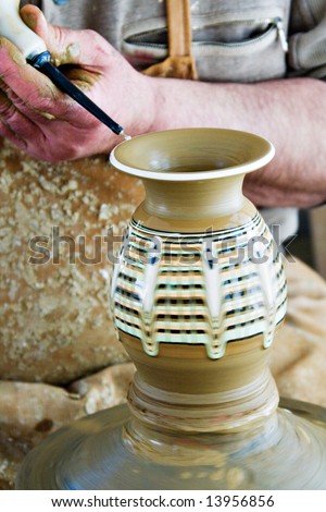Skillful potter crafting a vase from clay and painting it with black