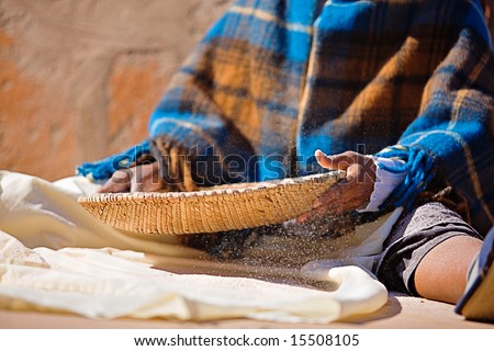 Portrait of African woman with a basket sieve straining sorghum, staple food in Africa
