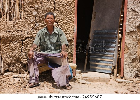 One of the few remaining bushman sitting down in front of his traditional shack, the indigenous people of Kalahari.