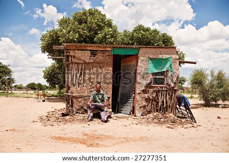 One of the few remaining bushman sitting down in front of his traditional shack, the indigenous people of Kalahari.