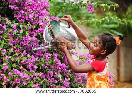 small african girl working in the garden watering the flowers, warm light