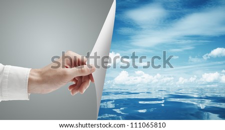 hand turn page to blue sky and still sea surface