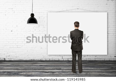 businessman looking empty poster in brick room