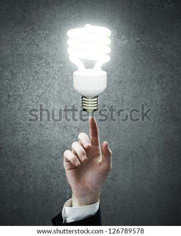 hand pointing to energy saving lamp  on gray background