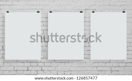 brick wall with three white poster