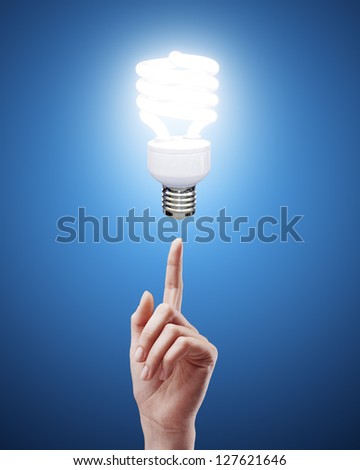 hand pointing to energy saving lamp on blue background