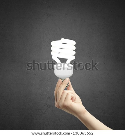 hand holding energy saving lamp on a concrete background