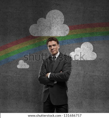 man with hands in pocket and rainbow on wall