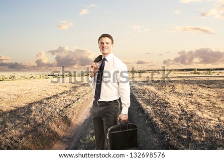 man with briefcase standing on a country road