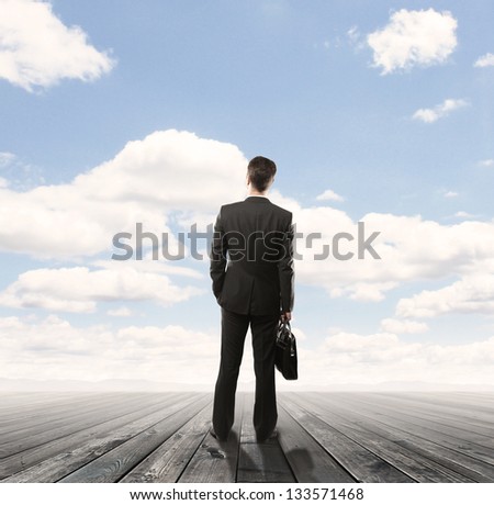 businessman standing on wooden floor and looking  blue sky
