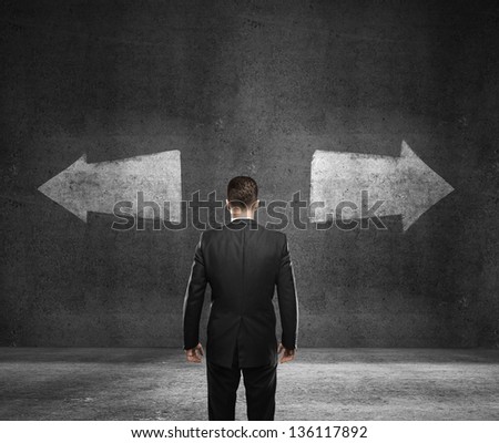 businessman standing and looking on drawing arrows on wall