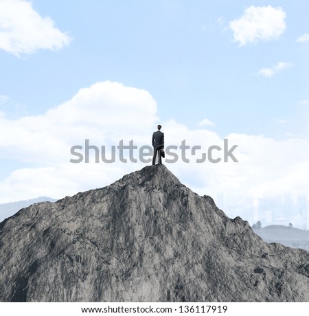 businessman with laptop standing on mountain