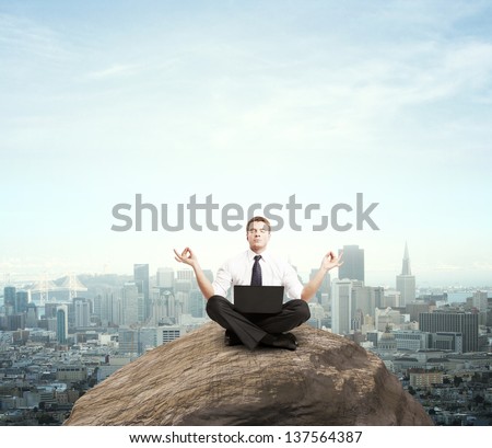 businessman sitting with laptop on mountain