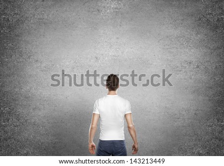 young man standing back and concrete wall